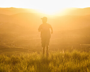homem caminhando com montanhas ao fundo na golden hour