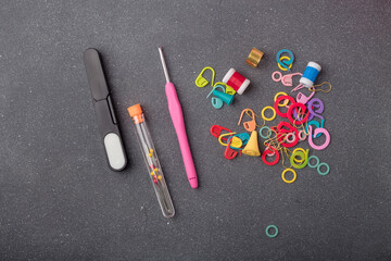 Crocheting tools kit. Set of crochet hook, thimble, pins, markers and other equipment for creative handicraft on grey background. Closeup, top view