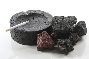 Lit cigarette in black ashtray of volcanic stone