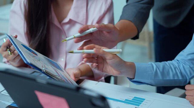 Corporate team working together, reviewing financial data on digital tablet, strategizing in modern office setting with professional atmosphere