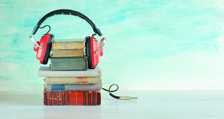 audio book concept with row of books and vintage headphone on blue...
