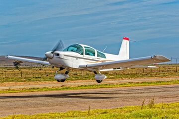 Powerful white and brown, low wing, single engine aircraft taking off from a small airfield in the Western Cape, South Africa