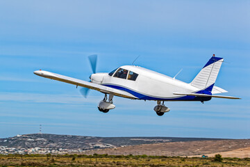 A popular, white and blue, single engine low wing aircraft just after take off from an airstrip in the Western Cape, South Africa