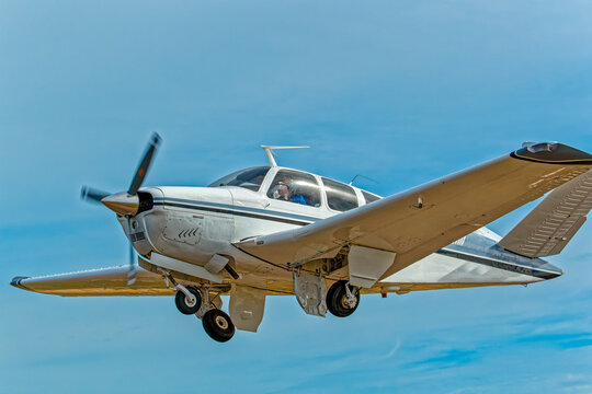 Six-seat white aircraft with black and blue stripes and retracting undercarriage and unique V shaped tail against blue sky in the Western Cape, South Africa