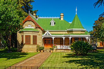 Gabled sandstone Victorian style house with a green roof and decorative turret in a small Little Karoo town in the Western Cape, South Africa © geoffsp