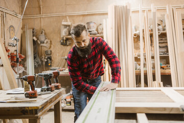 Carpenter Measuring Wood in Workshop