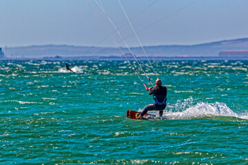 Kite surfer speeding through the water in a strong wind at the iconic lagoon at Langebaan Beach in the Western Cape, South Africa