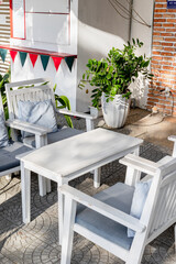 Outdoor cafe setting with white wooden chairs and green plant