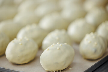 White chocolate coated pastry balls on baking tray in factory