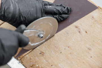 Gloved hands using pizza cutter to slice croissant dough in bakery factory, top view