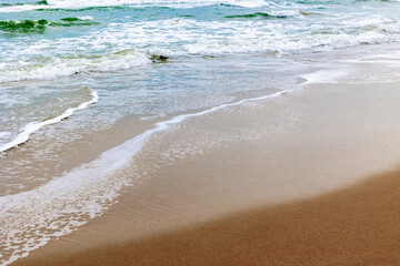 Tranquil waves on sandy beach with gentle surf and clear skies