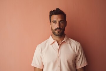 A man in a pink shirt is standing in front of a pink wall
