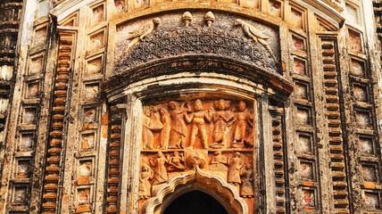 Terracotta depiction of Lord Krishna playing the flute atop a tree while Gopikas (cowherd women)...