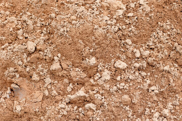Textured brown soil surface with small rocks and uneven terrain