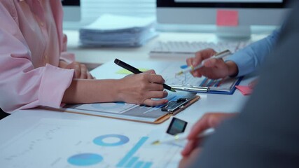 Professional team analyzing financial reports, gesturing at graphs, collaborating on corporate performance and strategic planning in modern workplace setting
