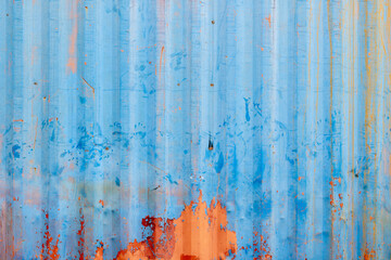 Rusty blue and orange corrugated metal surface with peeling paint