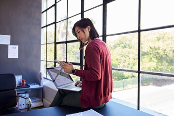 Casual business woman working on laptop in modern office