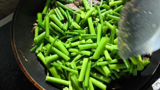 Frying  onion flower stem with pork liver in pan, in door  Chiangmai  Thailand.