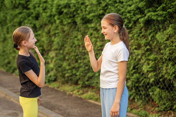 Fototapeta premium Meeting. Two tween girls enjoying a playful moment together while practicing gestures outdoors