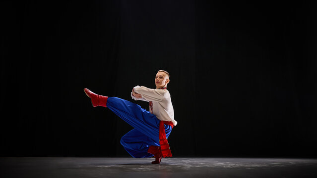 Ukrainian dancer in flowing motion, red boots and blue trousers creating dynamic contrast, expressing rhythm and connection to cultural roots. Concept of traditions, folk style, art and history. Ad