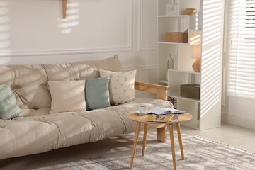 Beautiful sofa with cushions and coffee table in living room. Interior design