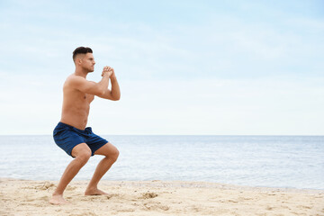 Muscular man doing exercise on beach, space for text. Body training