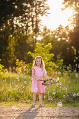 Naklejka premium Joyful girl on a sunny street surrounded by colorful soap bubbles, perfect for themes of summer, fun, childhood, play, and outdoor happiness