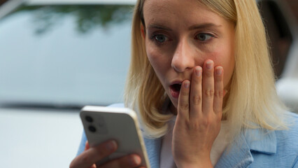 Surprised stressed anxious Caucasian buyer woman lady businesswoman female using mobile phone in city girl owner driver looking screen shock car problem bad news online automobile trouble rent auto