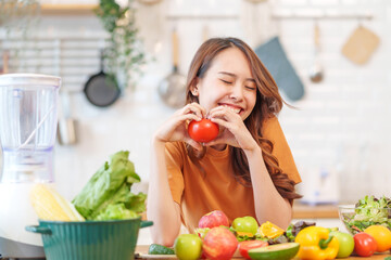 portrait freshy young asian woman having fun in the kitchen,hand holding ripe tomato for cook,healthy food,nutrition,vitamin,beauty,health