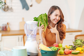 portrait young asian woman having fun in the kitchen,hand holding lettuce posing to camera,healthy food,nutrition,vitamin,health