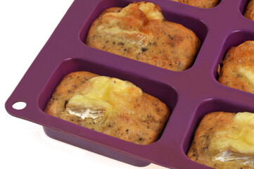 Petits cakes au fromage faits maison dans un moule en silicone en gros plan sur fond blanc