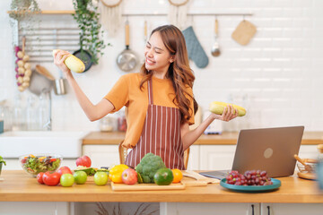 cheerful young asian woman learn to cook healthy food on social media via laptop in the kitchen,healthy lifestyle,nutrition,vitamin,beauty and health