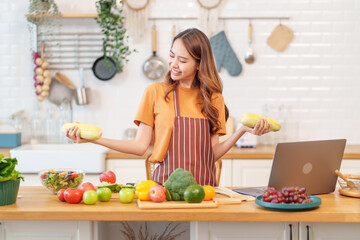 cheerful young asian woman learn to cook healthy food on social media via laptop in the kitchen,healthy lifestyle,nutrition,vitamin,beauty and health
