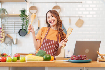 cheerul young asian woman cooking healthy food show on live streaming by laptop online in modern kitchen