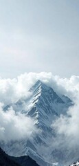 Obraz premium Gray clouds envelop the summit of a snow-capped mountain, misty, hazy