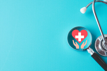 Top view of Magnifying glass focus on Hand Holding Red Heart over blue background with...
