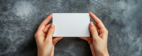 Female hands holding blank card on dark textured background