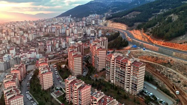 The video shows a multi-story residential construction site. Buildings are at different stages; some in the rough construction phase. The site includes roads, material areas,situated on a hillside.