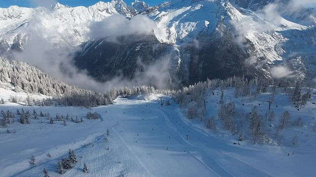 Drone aerial view over Brevent Ski Resort in Chamonix area, French Alps. Stunning Alpine mountain landscape on a morning day with blue sky. Amazing winter beauty with snow covered trees, mountain peak
