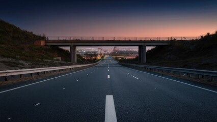 Obraz premium Wide empty asphalt highway under an overpass leading to a city skyline at dusk with soft purple and orange hues in the sky.
