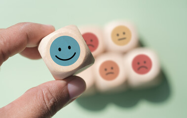 Hand holding wood cube with smile icon, World mental health day or feedback rating concept,...