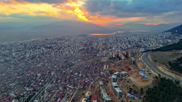 The video shows a wide cityscape at sunset with completed multi-story residential buildings in the foreground. The housing appears to be part of a large-scale residential construction project.