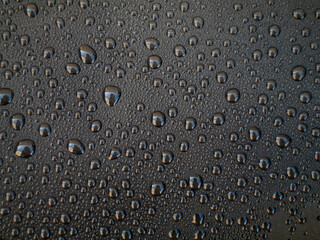 A close up of a black surface with many small drops of water