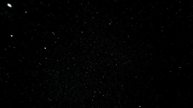 Sparkling particles on black background. Abstract motion, glitter effect, space concept. For presentation, overlay, animation, intro, outro, background.