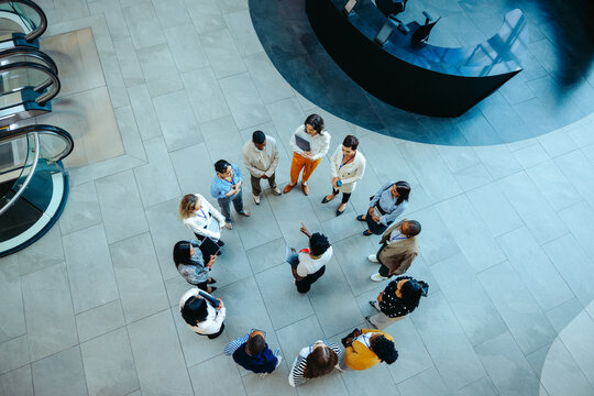 Team gathering in a circular formation within a modern office lobby