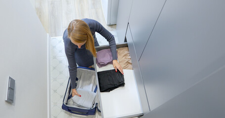 Woman Organizing Clothes in Drawer and Suitcase