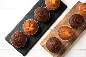 Delicious variety of fresh muffins displayed on wooden and slate serving boards