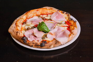 Pizza tradizionale napoletana con sugo di pomodoro, mozzarella,. funghi, prosciutto cotto e basilico fresco 