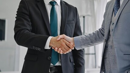 Securing the Deal: Two businessmen in sharp suits shake hands, signifying a successful business agreement or partnership. A powerful image of trust and collaboration.