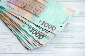 Big amount of ukrainian new one hundred hryvnia money bills with modern design on white wooden table. Financial concept, business